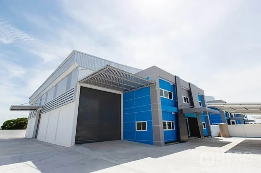 Factory for rent in Bang Phli, Samut Prakan - Modern blue-and-gray factory exterior with large roller shutter, canopy, and wide concrete yard in Bang Phli.