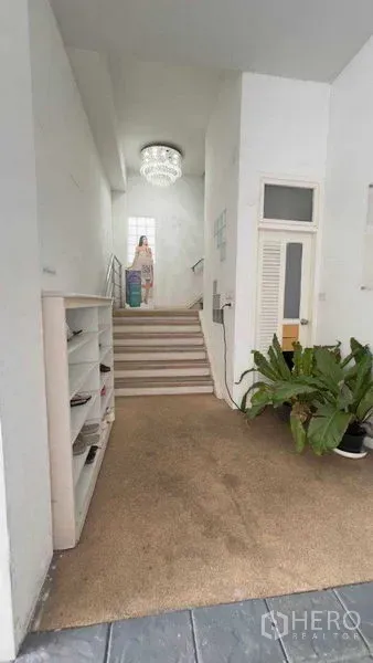 Standalone for rent in Khlong Toei, Bangkok - Entrance stairwell with chandelier, shoe rack and indoor plants.