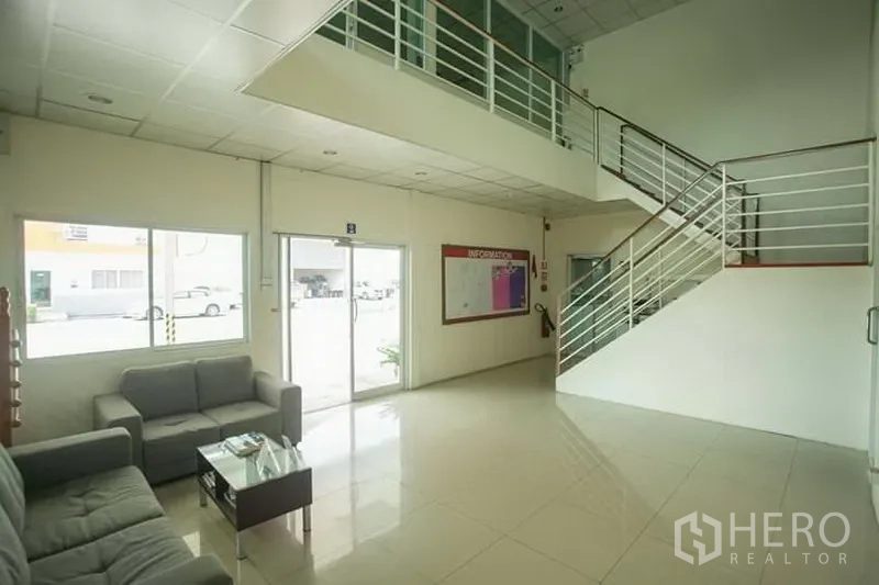 Factory for rent in Phra Nakhon Si Ayutthaya - Clean office lobby with tiled floors, glass entrance, sofa seating, and a staircase to the mezzanine.