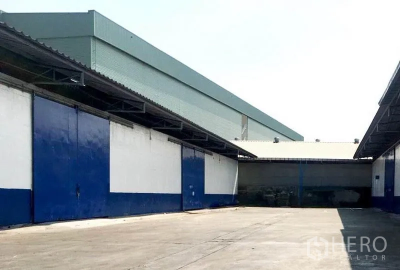 Warehouse for rent in Bang Phli, Samut Prakan - Outdoor yard between warehouse blocks with big blue doors, sheltered dock and ample truck turning space.