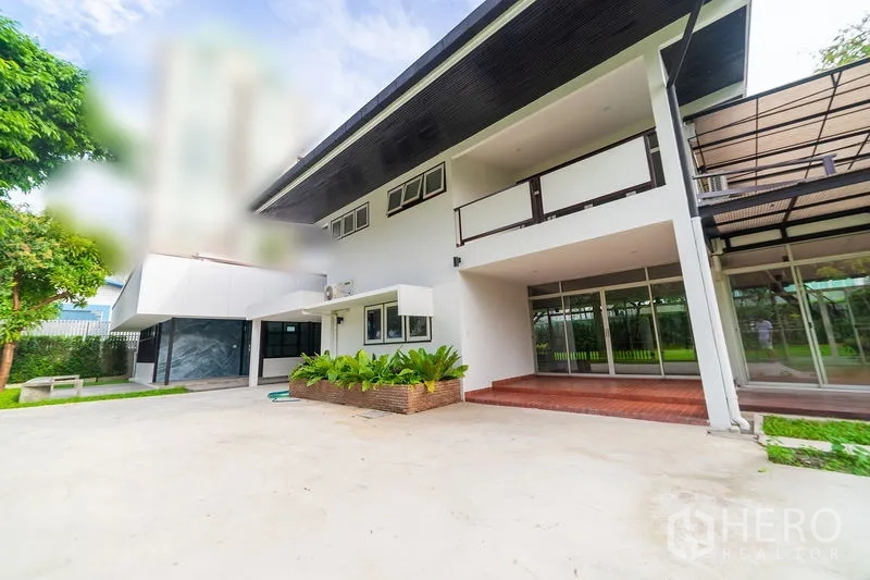 Detached House for rent in Khlong Toei, Bangkok - Modern two‑storey detached house with covered terrace, wide driveway and greenery.
