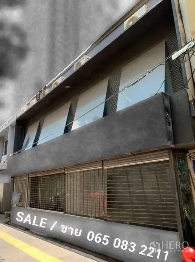 Shophouse for sale in Khlong Toei, Bangkok - Street-facing shophouse exterior with dark facade, wide roller shutters and upper windows.
