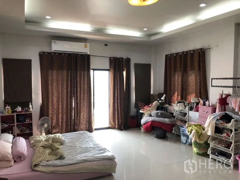 Detached House for sale in Lam Luk Ka, Pathum Thani - Spacious bedroom with brown curtains and glossy floor tiles.