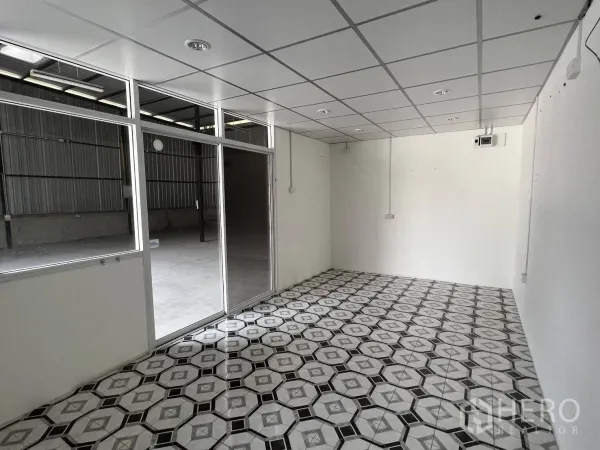 Warehouse for rent in Lat Krabang, Bangkok - Bright office room with drop ceiling and patterned tile floor facing the warehouse floor.