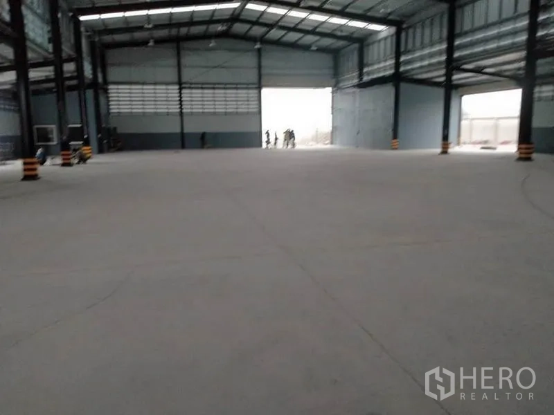 Factory for rent or sale in Phanat Nikhom, Chon Buri - Vast factory floor facing a large roller shutter opening under a tall metal roof.