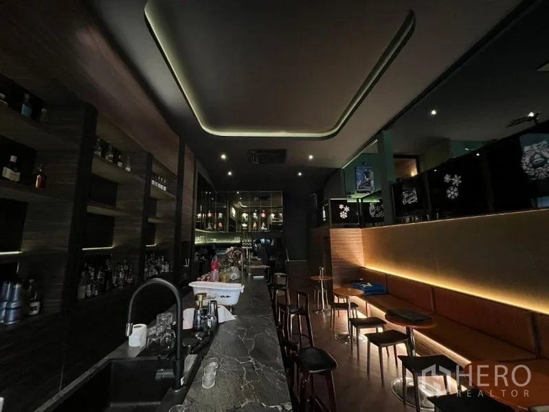 Retail Space for rent in Watthana, Bangkok - Dimly lit bar interior with long stone counter, backlit shelving and stools.