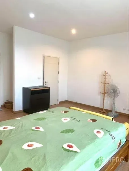 Townhouse for rent in Suan Luang, Bangkok - Spacious bedroom angle showing white walls, wood floors and a door to storage.