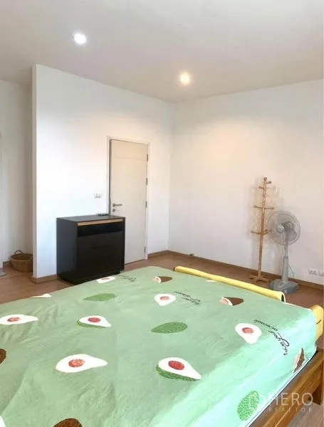 Townhouse for rent in Suan Luang, Bangkok - Spacious bedroom angle showing white walls, wood floors and a door to storage.