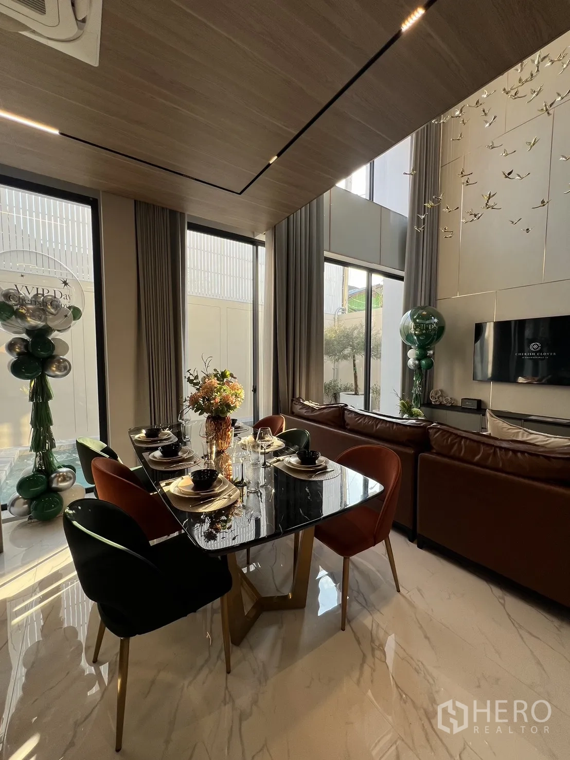 Detached House for sale in Lat Phrao, Bangkok - Dining area with marble floors, glossy black table and tall windows beside the lounge.