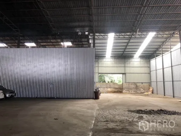 Warehouse for rent in Nong Chok, Bangkok - Well-lit warehouse section with skylight roof panels, metal cladding, and expansive concrete floor suitable for storage or operations.