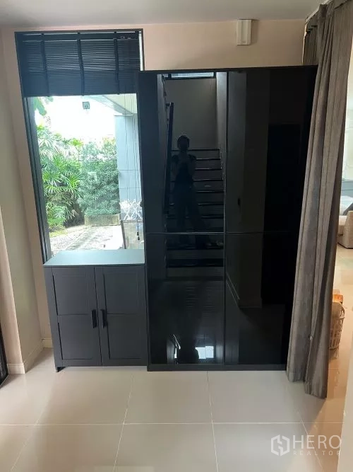 Detached House for rent in Bang Kapi, Bangkok - Entry nook featuring a sleek black wardrobe beside a window near the staircase.