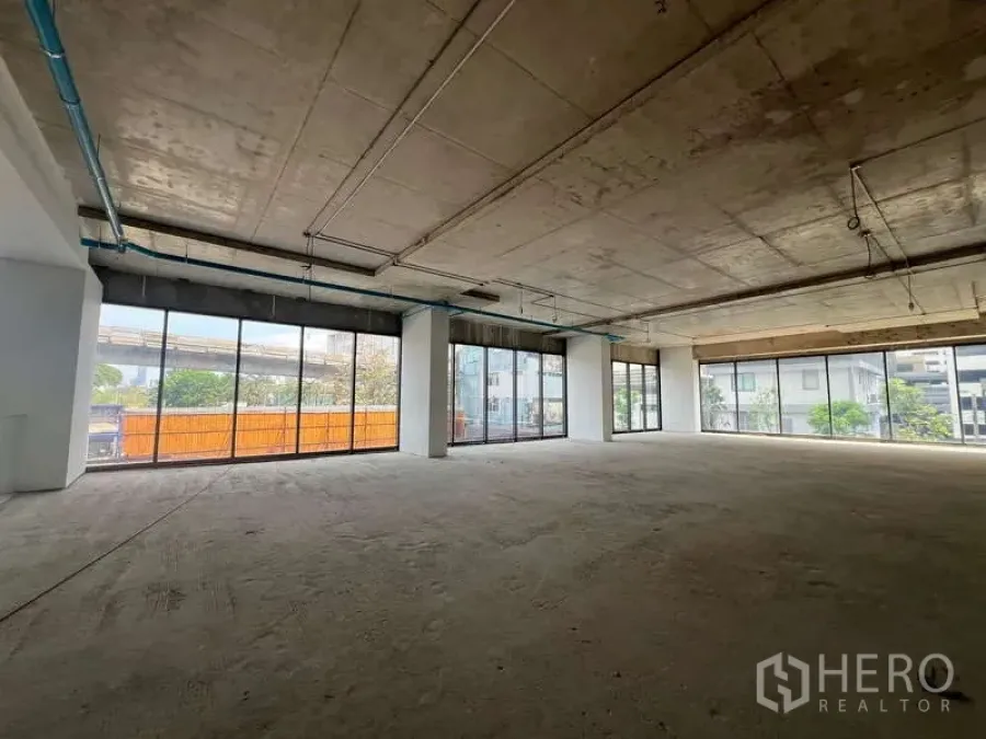Retail Space for rent - Unfinished retail floor with floor-to-ceiling glass walls, open layout and exposed concrete ceiling facing the street.