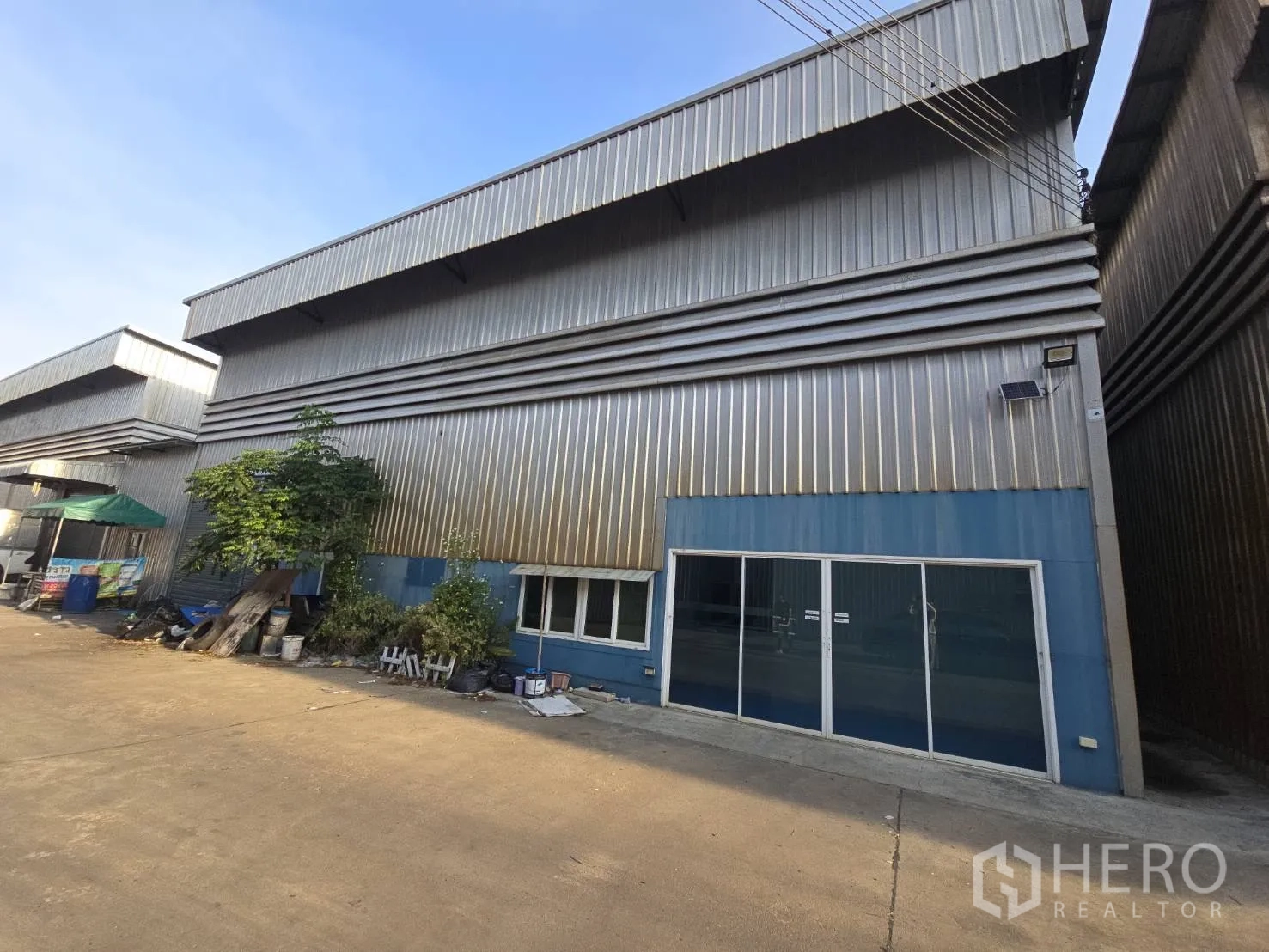 Warehouse for rent in Bang Phli, Samut Prakan - Front facade of the warehouse with sliding glass entry on a concrete drive.