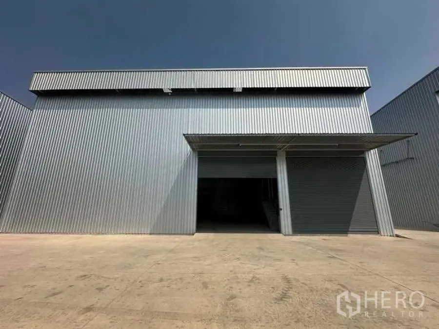 Factory for rent in Wang Noi, Phra Nakhon Si Ayutthaya - Front of a corrugated-metal factory with twin roller shutters and a wide concrete loading apron under a canopy.