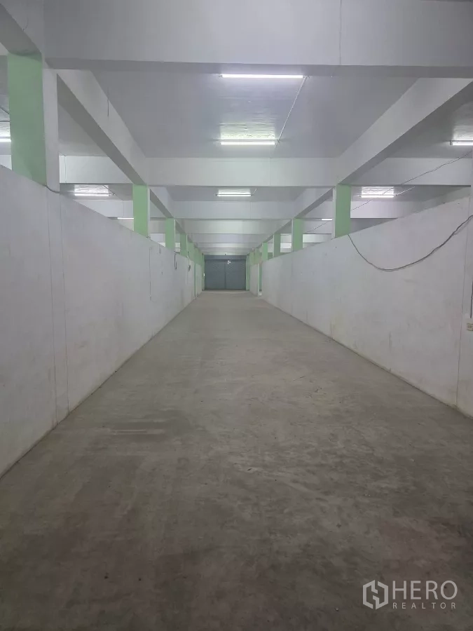 货栈 出租在Bang Khun Thian, Bangkok - 狭长储物通道，白色墙面、混凝土地面，尽头为卷帘门
