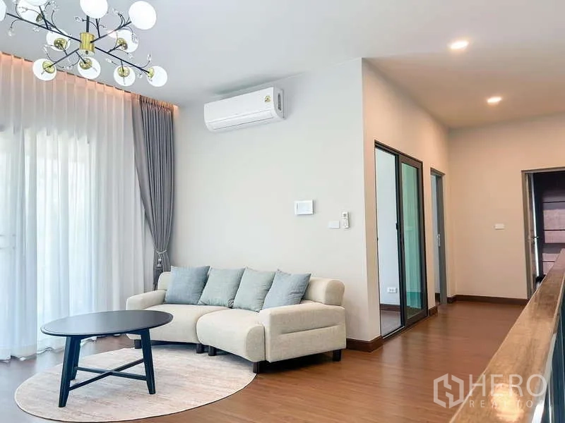 Detached House for rent in Bang Phli, Samut Prakan - Upstairs family lounge with sofa, round coffee table, chandelier and sheer drapes to balcony.