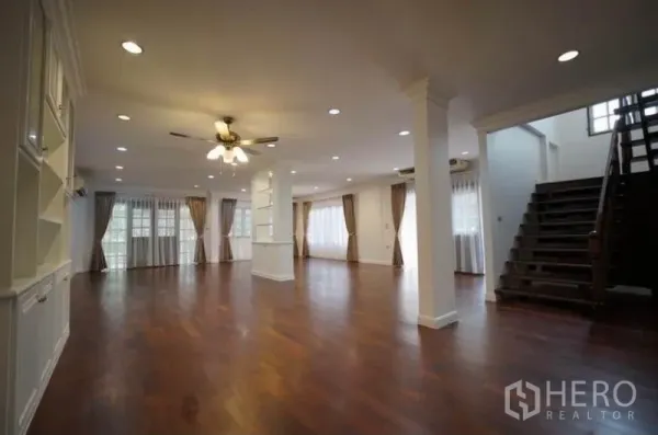 Detached House for rent in Bang Phli, Samut Prakan - Spacious open-plan living area with wood floors, recessed lighting and a staircase.