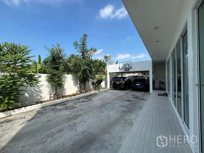 独立式住宅 出租在Lat Krabang, Bangkok - 私家车道与有顶车棚，设篮球框，墙边绿植成行。