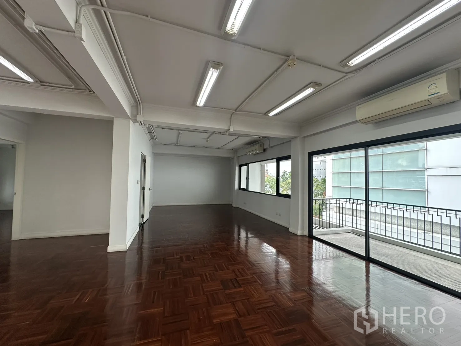 Office Space for rent in Watthana, Bangkok - Elongated open office zone facing a balcony, multiple AC units, and overhead lighting.