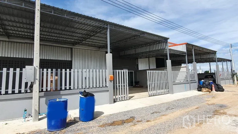 Warehouse for rent in Lam Luk Ka, Pathum Thani - Street-facing facade of warehouse units with wide gated bays and open driveway.