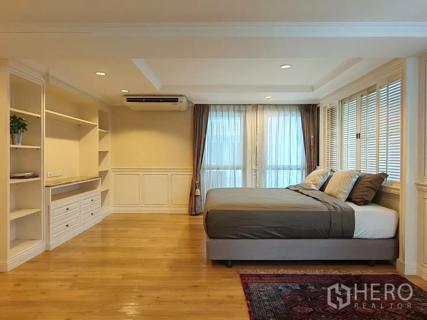 Condominium for rent in Pathum Wan, Bangkok - Master bedroom with king bed, built-in storage and corner windows.