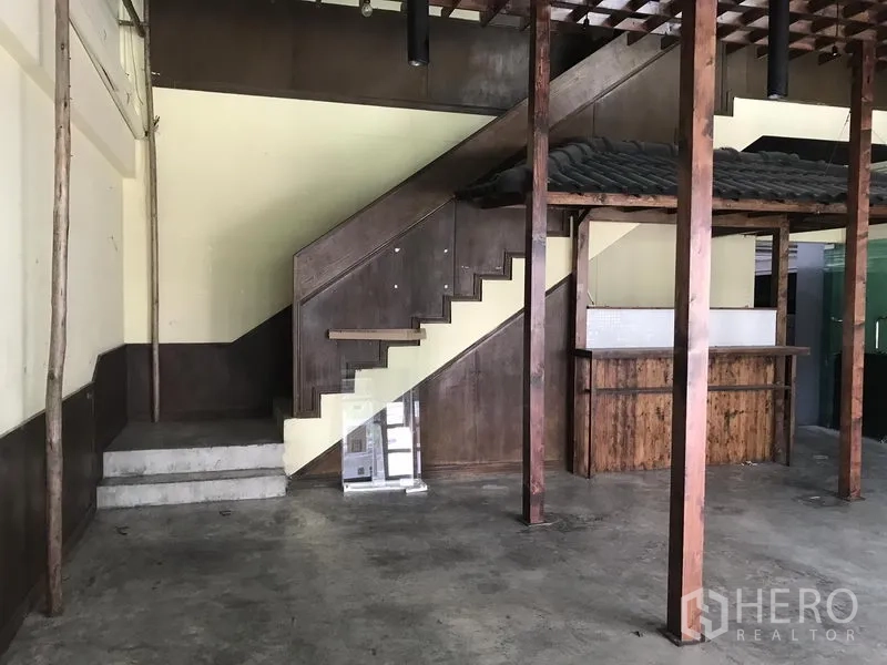 Retail Space for rent in Khlong Toei, Bangkok - Retail space showing wooden staircase, built-in counter, exposed beams and polished concrete floor.