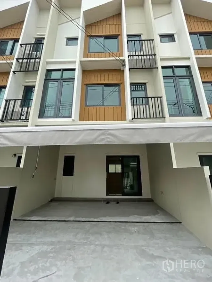 Townhouse for rent in Prawet, Bangkok - Front view of the townhouse facade showing covered carport and balconies.