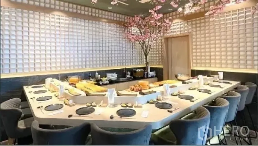 Retail Space for rent - U-shaped sushi counter with multiple seats in a modern Japanese-style dining room, grid-pattern walls and cherry blossom decor.