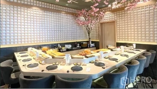 Retail Space for rent - U-shaped sushi counter with multiple seats in a modern Japanese-style dining room, grid-pattern walls and cherry blossom decor.