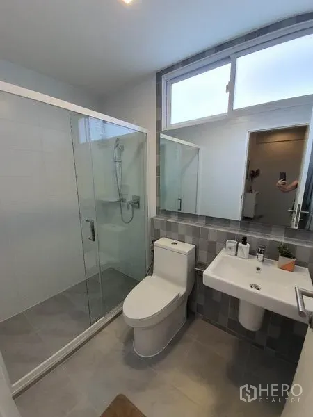 Detached House for rent in Prawet, Bangkok - Contemporary bathroom with glass-enclosed shower, toilet and wall mirror.
