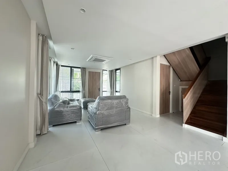 联排别墅 出租在Watthana, Bangkok - 采光充足的客厅，新沙发与木楼梯