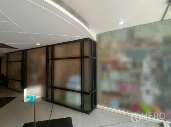 Retail Space for rent in Watthana, Bangkok - Interior corridor view showing black-framed glass partitions and curved white ceiling near a retail entrance.