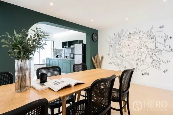 Office Space for rent in Khlong Toei, Bangkok - Communal pantry and dining zone with green cabinetry, arched opening, wooden table, rattan chairs and a city map mural.