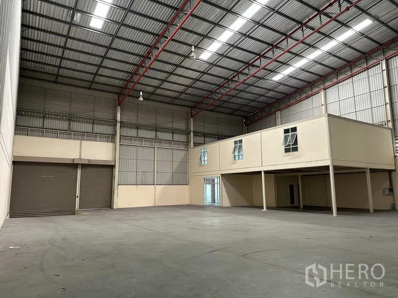 Factory for rent in Bang Phli, Samut Prakan - Wide factory floor with high-bay lighting, mezzanine offices and multiple rolling doors for logistics.