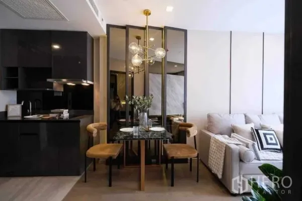 Condominium for rent in Watthana, Bangkok - Glossy black kitchenette beside a dining set and cozy sofa in a modern condominium.