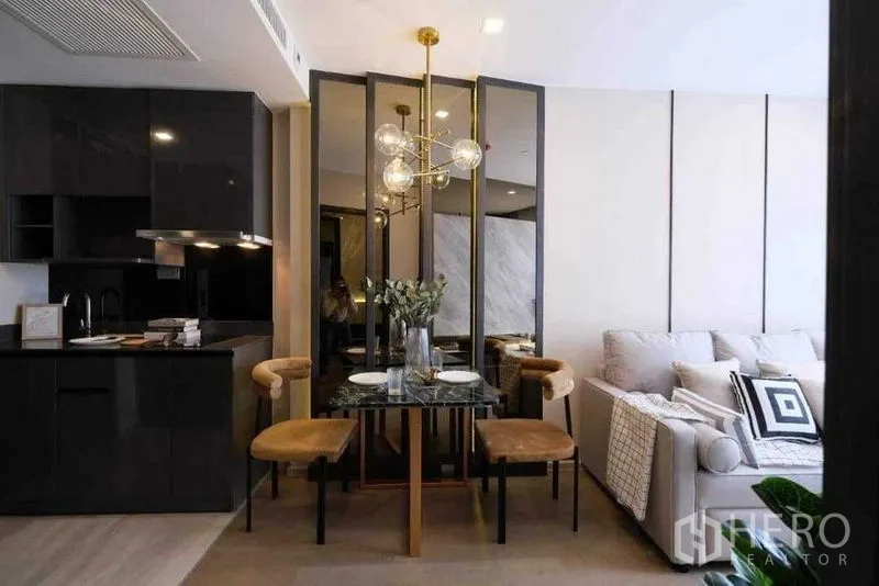 Condominium for rent in Watthana, Bangkok - Glossy black kitchenette beside a dining set and cozy sofa in a modern condominium.