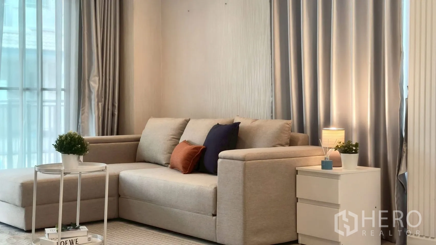 Detached House for rent or sale in Mueang Samut Prakan, Samut Prakan - Bright living corner with L-shaped sofa, side table and floor-to-ceiling drapes.