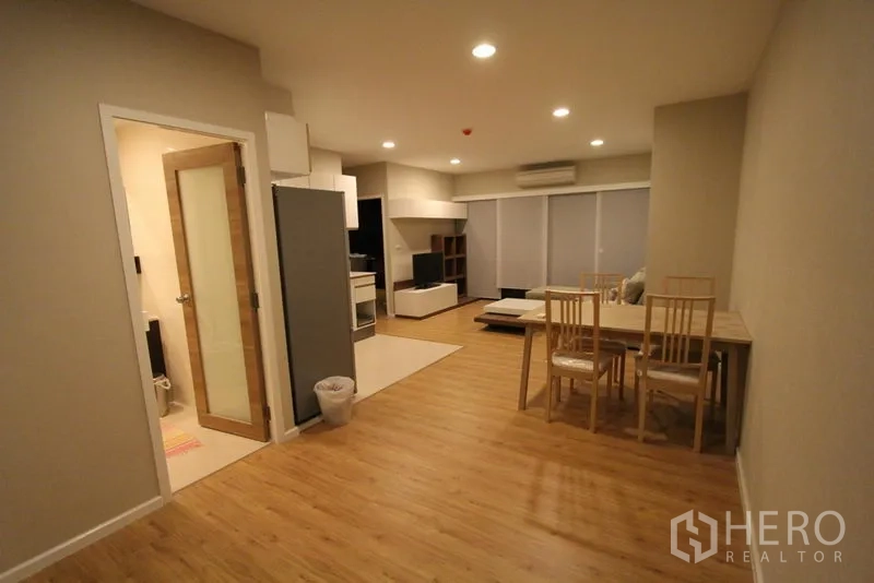 Condominium for rent in Pathum Wan, Bangkok - Spacious dining area leading to the living room with recessed lighting and wood floors.