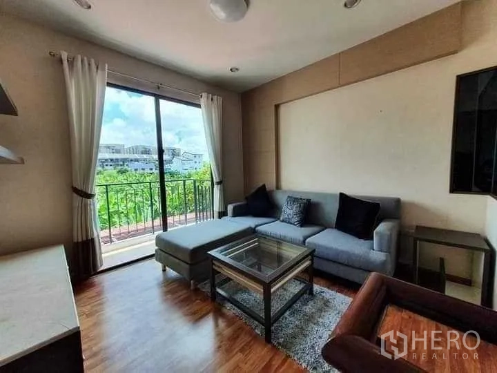 Townhouse for rent in Phra Khanong, Bangkok - Lounge opening to a balcony through sliding glass doors with green outlook.