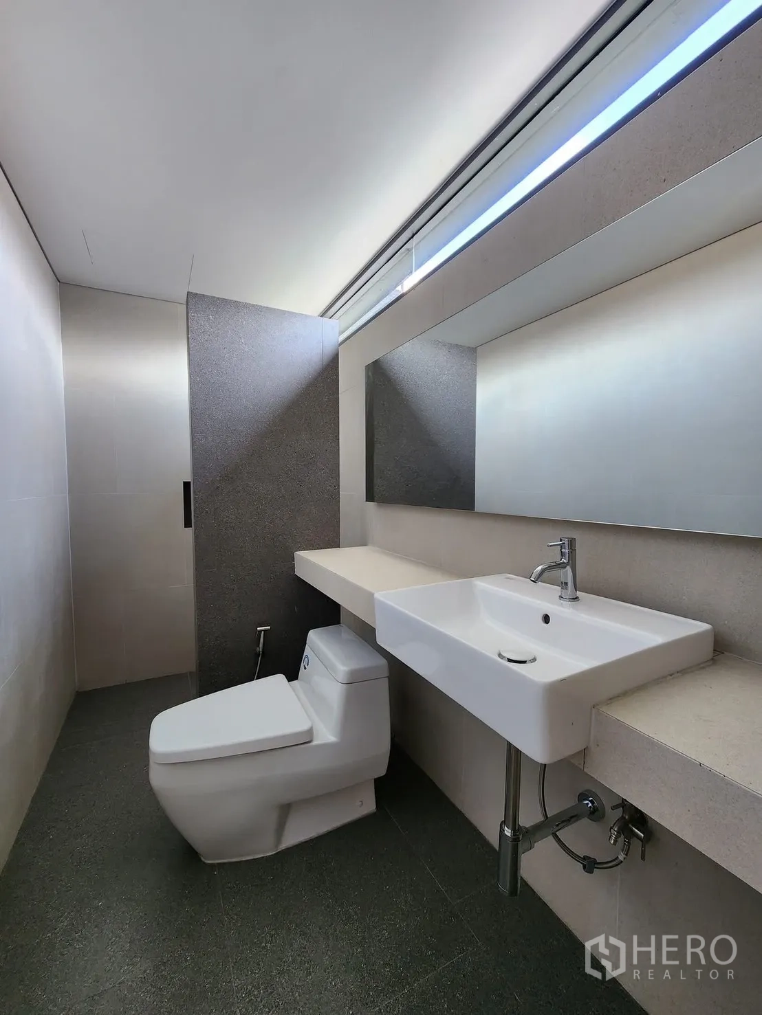 Home Office for rent in Chatuchak, Bangkok - Modern bathroom with wall-mounted sink, toilet, and high slit window.