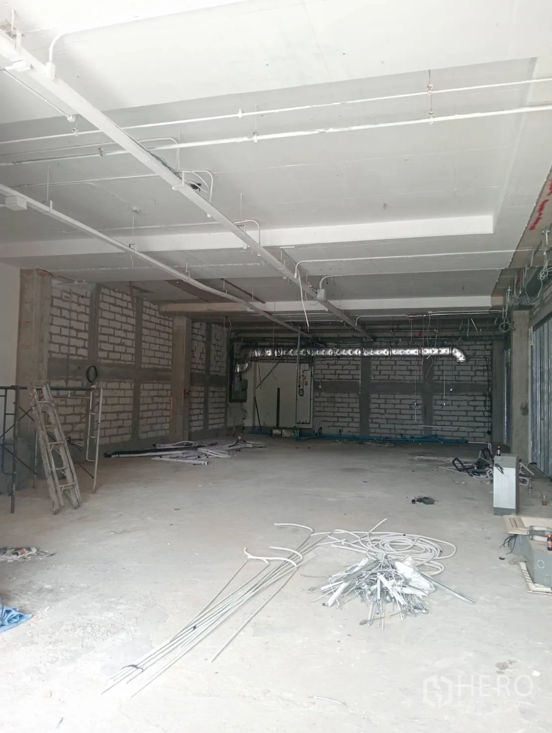 Retail Space for rent - Open-plan shop unit under construction with visible conduit and high slab ceiling.