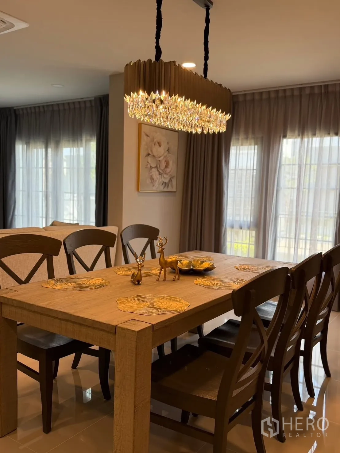 Detached House for rent in Bang Phli, Samut Prakan - Wood dining table by tall windows with sheer curtains and wall art.