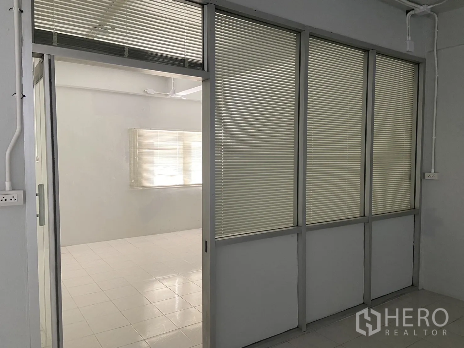 Shophouse for rent in Bang Na, Bangkok - Sliding glass partition with built-in blinds opening to a bright office room.