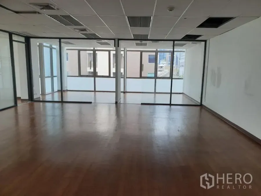 Office Space for rent in Khlong Toei, Bangkok - Open-plan office with wood flooring, glass-partitioned rooms and large windows providing natural light.