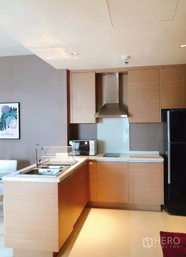 Condominium for rent in Khlong Toei, Bangkok - L-shaped kitchen with island sink, cooktop, hood and microwave.