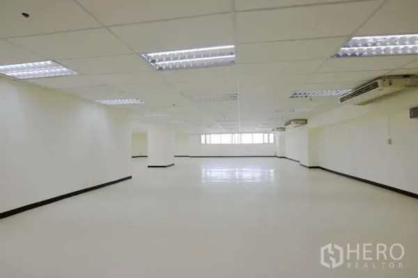 Office Space for rent - Open-plan workspace featuring grid ceiling lights, multiple AC units, and glossy floors.