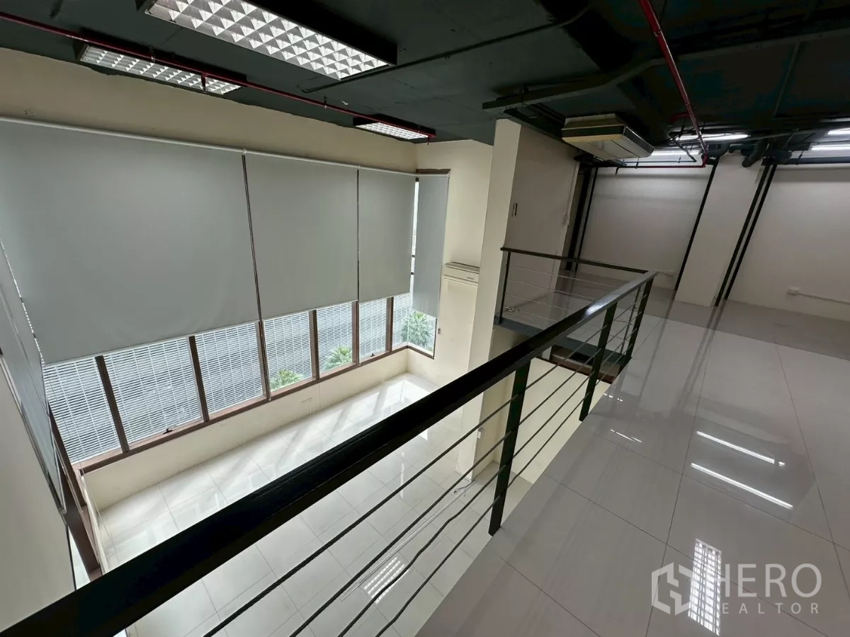 Office Space for rent in Khlong Toei, Bangkok - View along the mezzanine railing to tall windows with roller blinds.