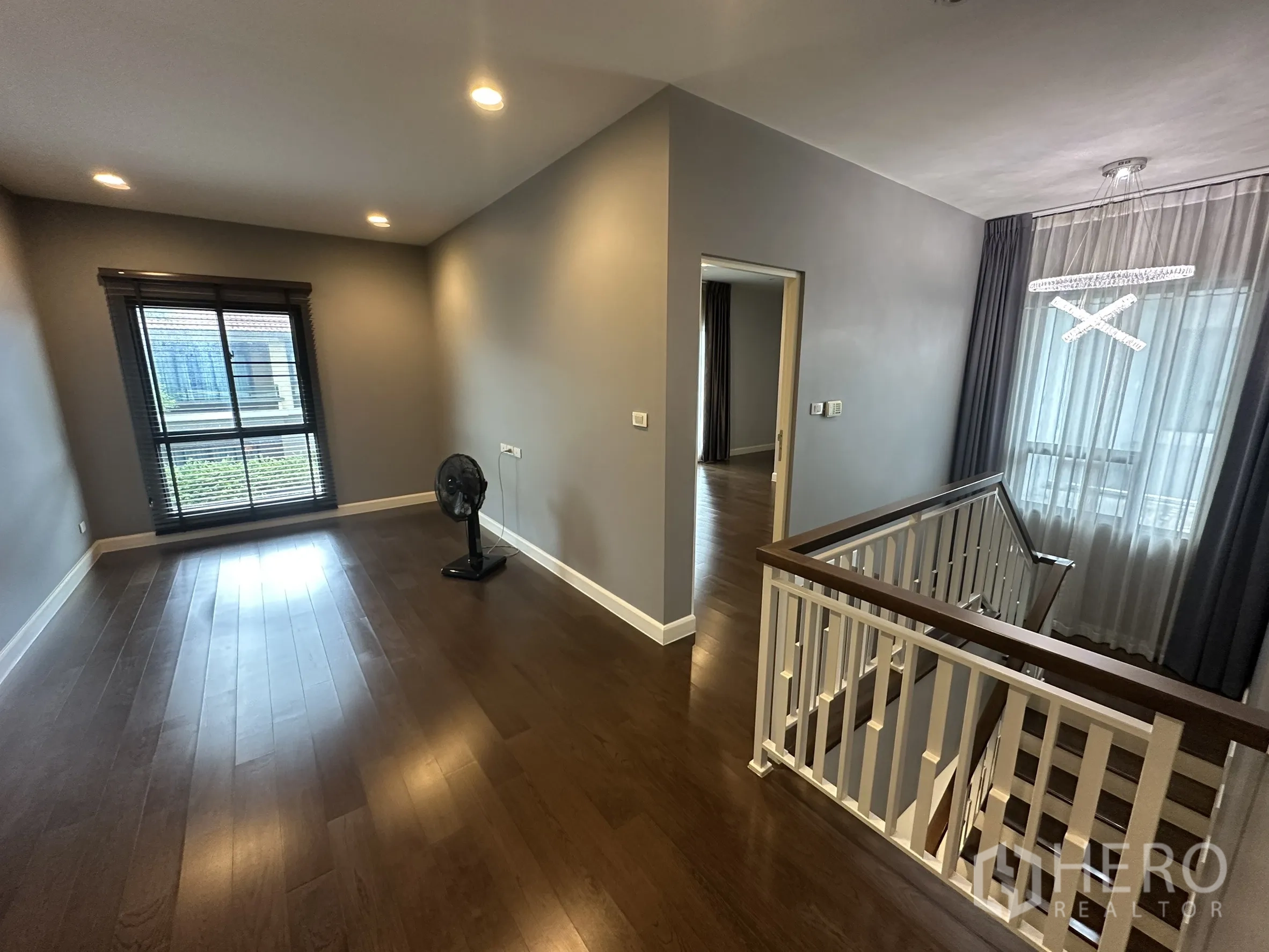 Detached House for rent in Lam Luk Ka, Pathum Thani - Upper landing with wooden floors, large window and white balustrade.