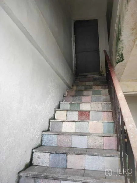 Shophouse for sale in Phra Khanong, Bangkok - Staircase finished with multicolored tiles and a metal handrail.