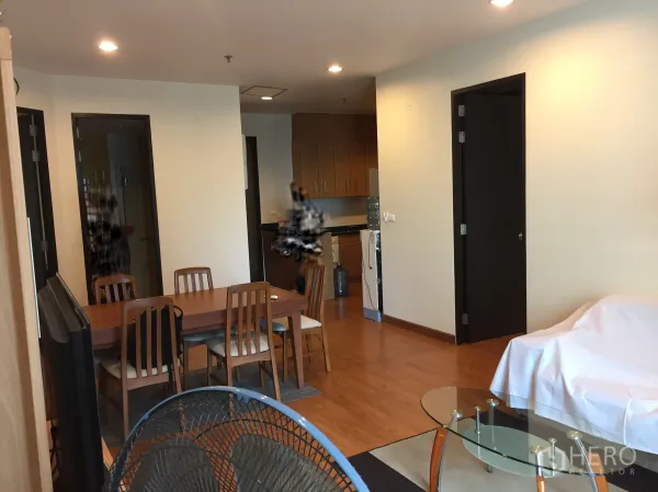 Condominium for rent in Khlong Toei, Bangkok - Open-plan dining area beside a compact kitchen with wooden cabinetry and a washer.